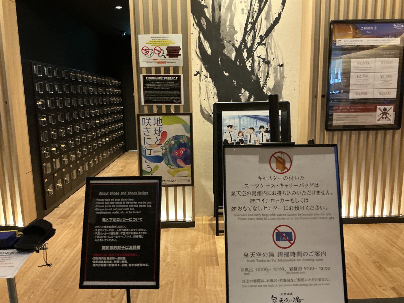 泉天空の湯の受付前の掲示。キャスター付きスーツケースの持ち込み禁止と清掃時間の案内